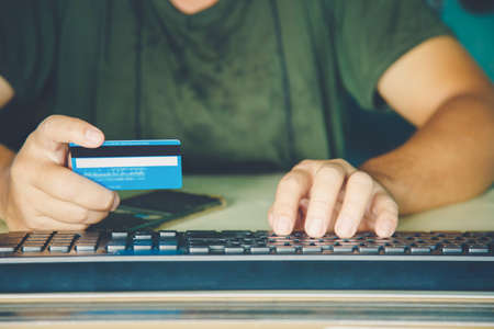 Close up a hands man holding credit card and use keyboard computer.の写真素材
