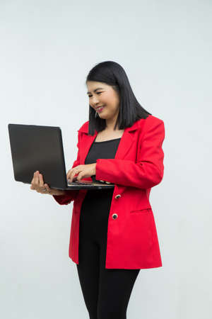 Portrait confident middle-aged Asian woman wearing pink casual wear pointing a finger to a tablet isolated on white backgroundの写真素材