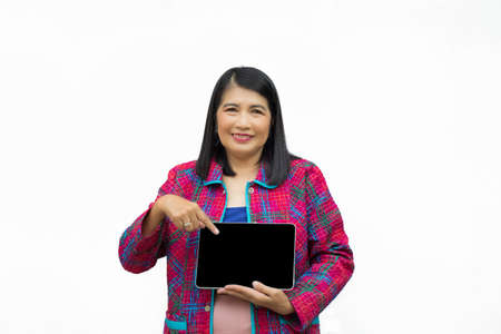 Portrait confident middle-aged Asian woman wearing pink casual wear pointing a finger to a tablet isolated on white backgroundの写真素材