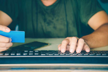 Close up a hands man holding a credit card and using a keyboard computer for shopping online.の写真素材