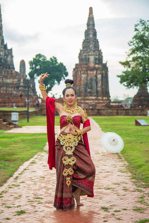 Portrait Asian woman in a red Thai dress posting with An old Buddhist temple at Wat Chai wattanara at Ayutthayaの写真素材