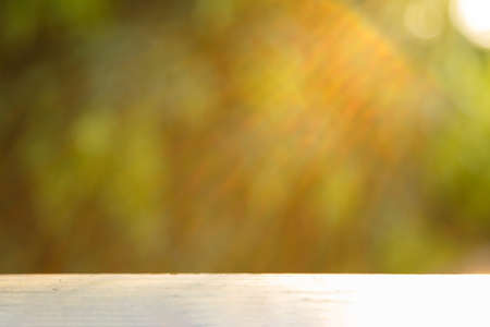 A white wooden table with abstract blurred nature and light for backgroundの写真素材