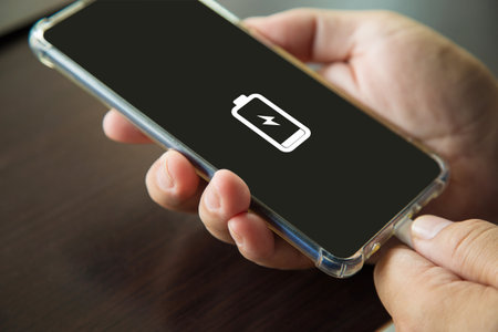 Man's hand unplugging a tablet charger on a wooden table in the wrong wayの写真素材
