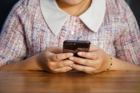 An Asian woman in casual clothes looking at a camera while using an electronic pen on a tablet on a wooden tableの写真素材