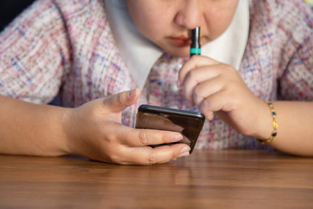 Smiling Asian woman in casual wear using her mobile to take a photo of a cup of coffee in a coffee shop.の写真素材