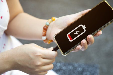 Close up a woman hands charging her mobile phone with charging icon