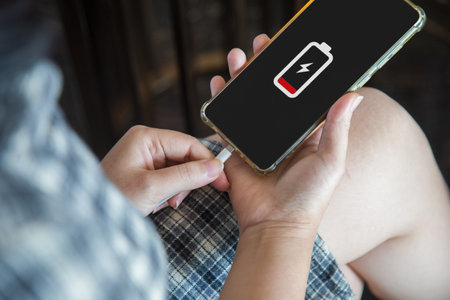 Close up a woman hands charging her mobile phone with charging icon