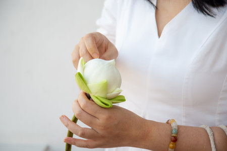 Close up an Asian woman in a white dress folding lotus flowers to worship Buddhaの写真素材