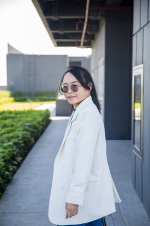 Portrait picture of a glasses Asian woman in white clothes with an outdoor background.の写真素材
