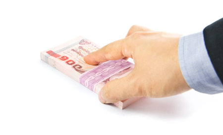 Hand holding a bulk of 100 baht Thailand banknote