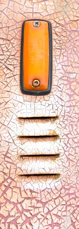 old electic light on orange paint flaking on grey metal surface textureの写真素材