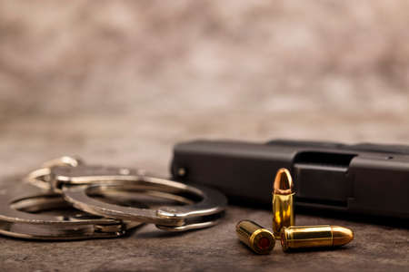 Handcuffs and Bullets with pistol handgun on texture backgroundの写真素材