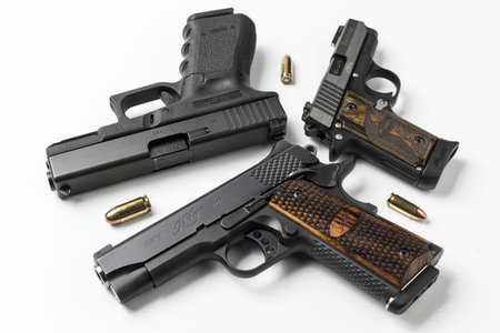 Automatic hand guns and ammunition on white background