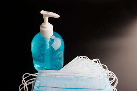 Alcohol gel hand sanitizer and disposable hygienic mask on black background , copy spaceの写真素材