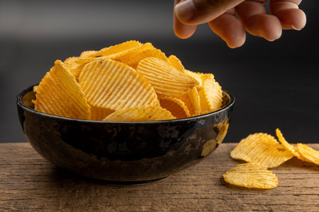 Hand take potato chips from bowl on black background
