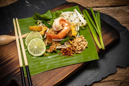 Thai style noodle or Pad Thai on cutting board with wooden background , Traditional food ,  Pad Thai is another famous Thai food , That foreigners know all over the worldの写真素材