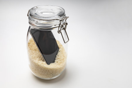 A wet smartphone is dried in rice on white background with a glass bottleの写真素材