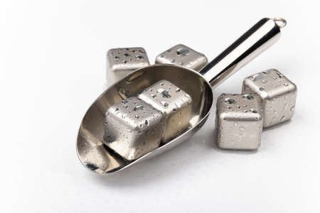 Stainless steel cubes simulating ice for cooling drinks with scoop on white backgroundの写真素材