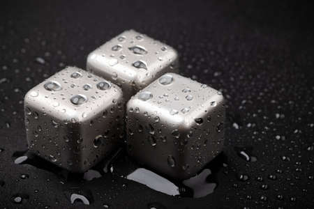 Stainless steel cubes simulating ice for cooling drinks with dew on black backgroundの写真素材