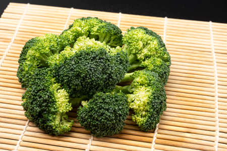 Fresh broccoli with drops of water isolated on bamboo mat backgroundの写真素材