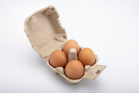 Open box with Chicken eggs in small paper tray on white background