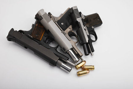 Guns , Difference size of Semi automatic pistol handguns with .45 bullets  on white background , The...