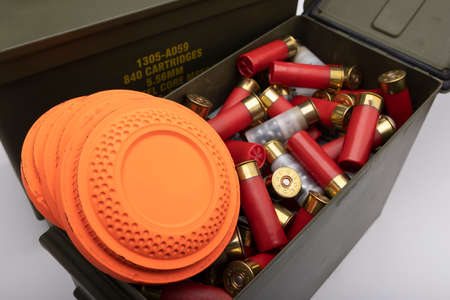 Flying clay target and bullet shotgun shell in green army ammo crate on white backgroundの写真素材
