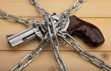 Revolver hand gun and metal chains on wooden background , Gun Control and safety conceptの写真素材