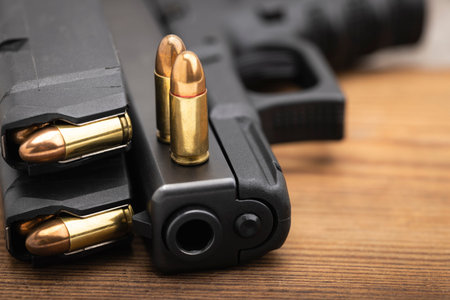 9 mm. ammunition magazines and automatic hand gun on wooden background