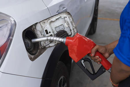 Holding a fuel nozzle and fill with gasoline at a gas stationの写真素材