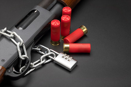 Gun safety , Combination key locked and shotgun with bullet shell on black background