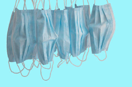 Hygienic masks hanging on a blue background waiting to be destroyed with clipping pathの写真素材