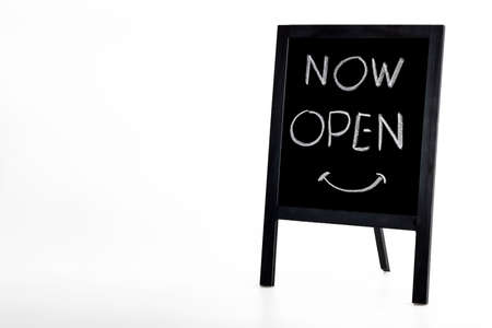 Hand writing 'Now Open' on small wooden vintage chalkboard on white backgroundの写真素材