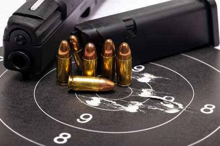 Gun bullets on bull eye paper target and semi automatic handgun backgroundの写真素材
