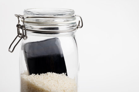 A wet smartphone is dried in rice and glass bottle on white backgroundの写真素材