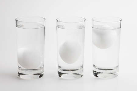 Eggs in water test on transparent glass , Egg freshness test on white background , Bad egg floats in waterの写真素材