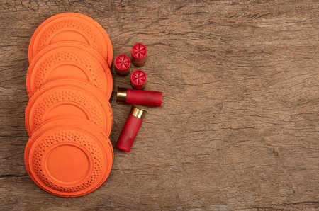 Flying clay pigeon target with shot gun bullet shell on wooden background , Gun shooting game