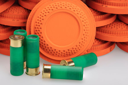 Stack of flying clay pigeon targets and shotgun shell bullets on white background , Gun shooting...