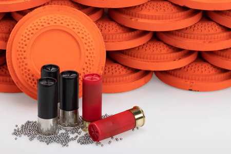 Black and red shotgun shell with birdshot and clay pigeon target on white background , Gun shooting...