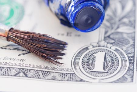 Brush and the tube with paint lie on banknotesの写真素材