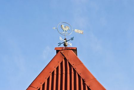 Vane on the roof of a country house on a background of blue skyの写真素材