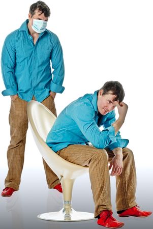 Sick and sad man sitting next to people in medical masksの写真素材