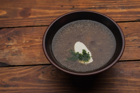 Soup in a clay pot on the table is made of woodの写真素材