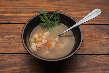Soup in a clay pot on the table is made of woodの写真素材