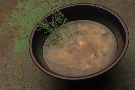 Soup in a clay pot on the table is made of woodの写真素材