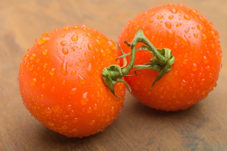 Wet red tomatoes with drops and vegetables for cookingの写真素材