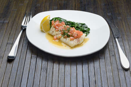 boiled fish in a plate with seasoning and spinachの写真素材