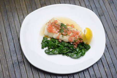boiled fish in a plate with seasoning and spinachの写真素材