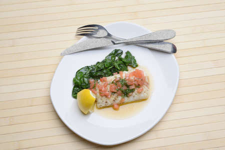 boiled fish in a plate with seasoning and spinachの写真素材