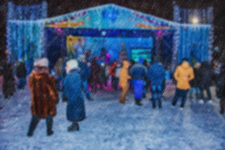 Blurred background of a winter landscape - people in the park to celebrate Christmas holiday. The performance of the artists on stage. Actors and musicians entertain the guests.の写真素材